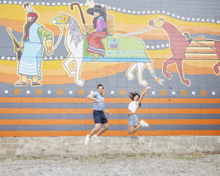 a couple jumping in front of a mural in calgary