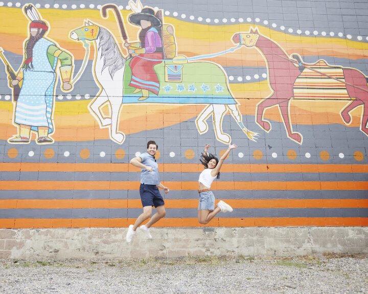 a couple jumping in front of a mural in calgary