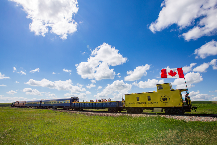 Canadian flag on the Aspen Crossing Train in the prairies under a blue sky near Mossleigh