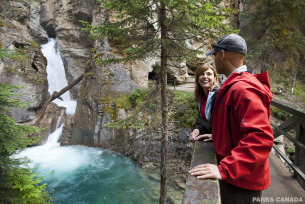 A couple stop to admire the view while hiking in Johnston Canyon in Banff National Park