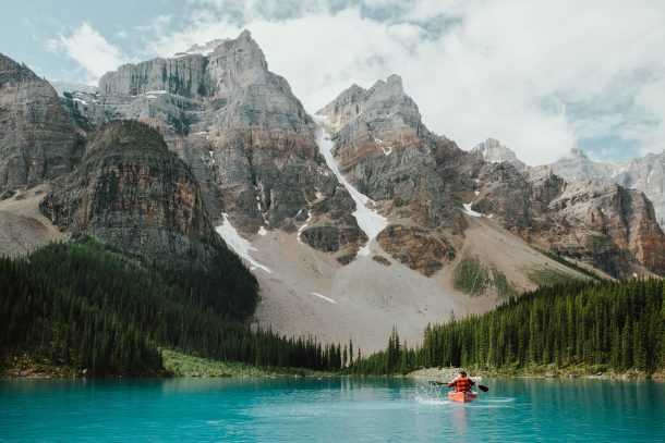 a man in a canoe on Moraine Lake surrounded by mountains in Banff National Park