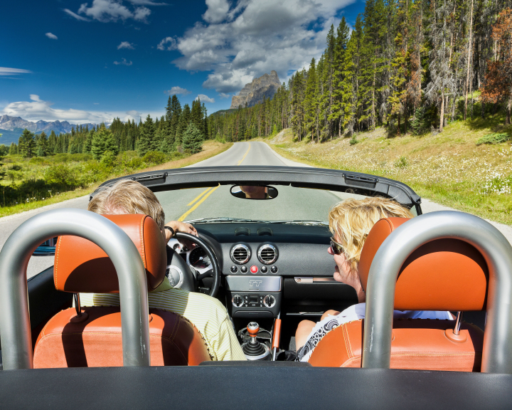 Couple in a convertible driving through Banff National Park in Alberta