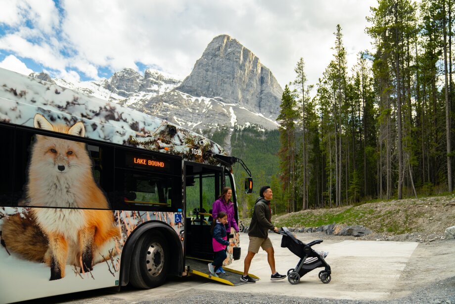 A family with a stroller gets off a bus at the Grassi Lakes Trailhead in Canmore.
