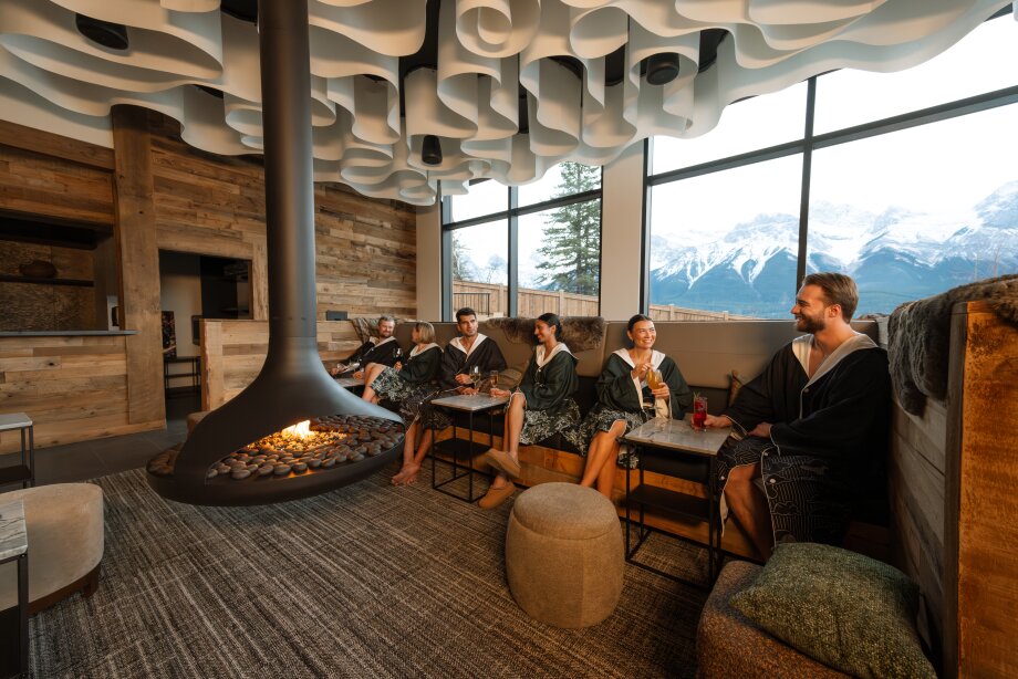 A group of spa goers in bathrobes relax indoors at Everwild Canmore - Nordic Spa & Hotel