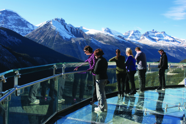 Visitors standing on the glass-floor platform of the Glacier Skywalk hovering 280 metres above Sunwapta Valley