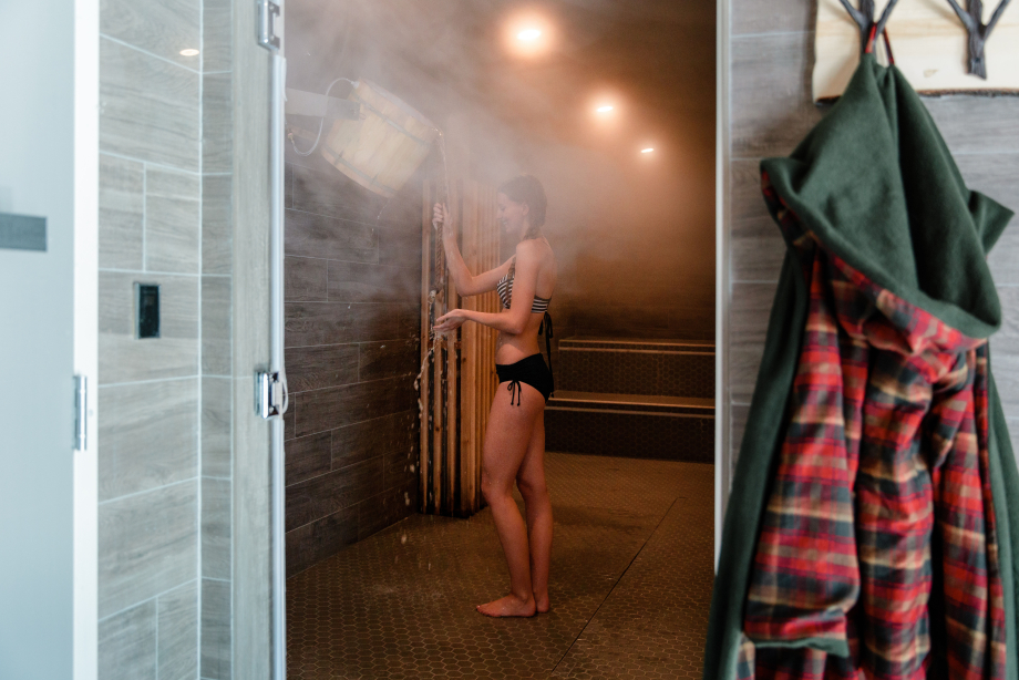 Woman in sauna shower at the Nordic spa at the Pomeroy Kananaskis Mountain Lodge