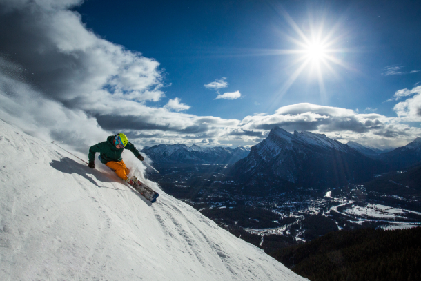 One person carving and skiing with a brilliant sun in the background at Mt. Norquay in Banff National Park