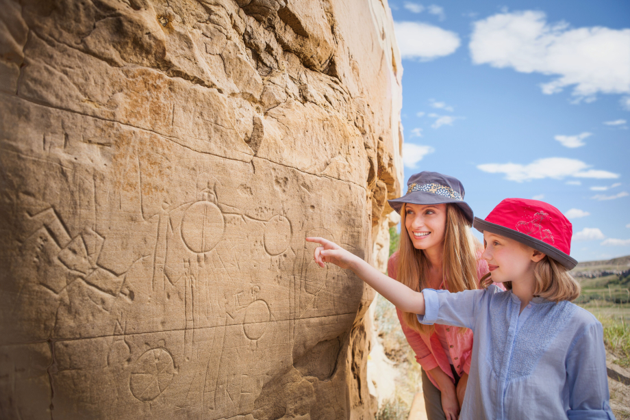 Mother and daughter looking and pointing to a rock while visiting Writing-on-Stone Provincial Park