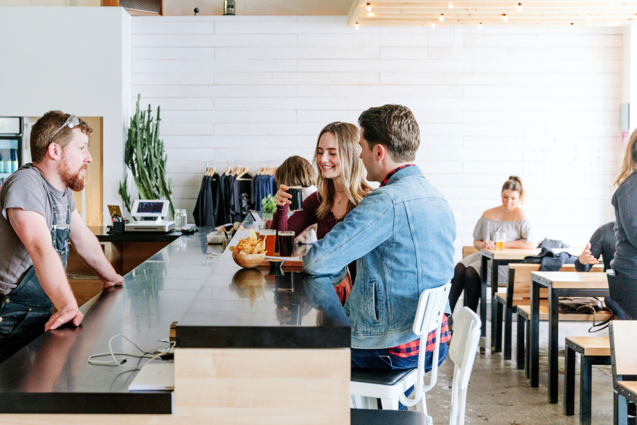 Bartender talking to a couple drinking a beer flight at a bar in Calgary