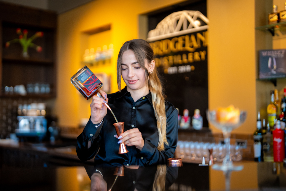 a bartender pours alcohol from a bottle into a bar measure at Bridgeland Distillery