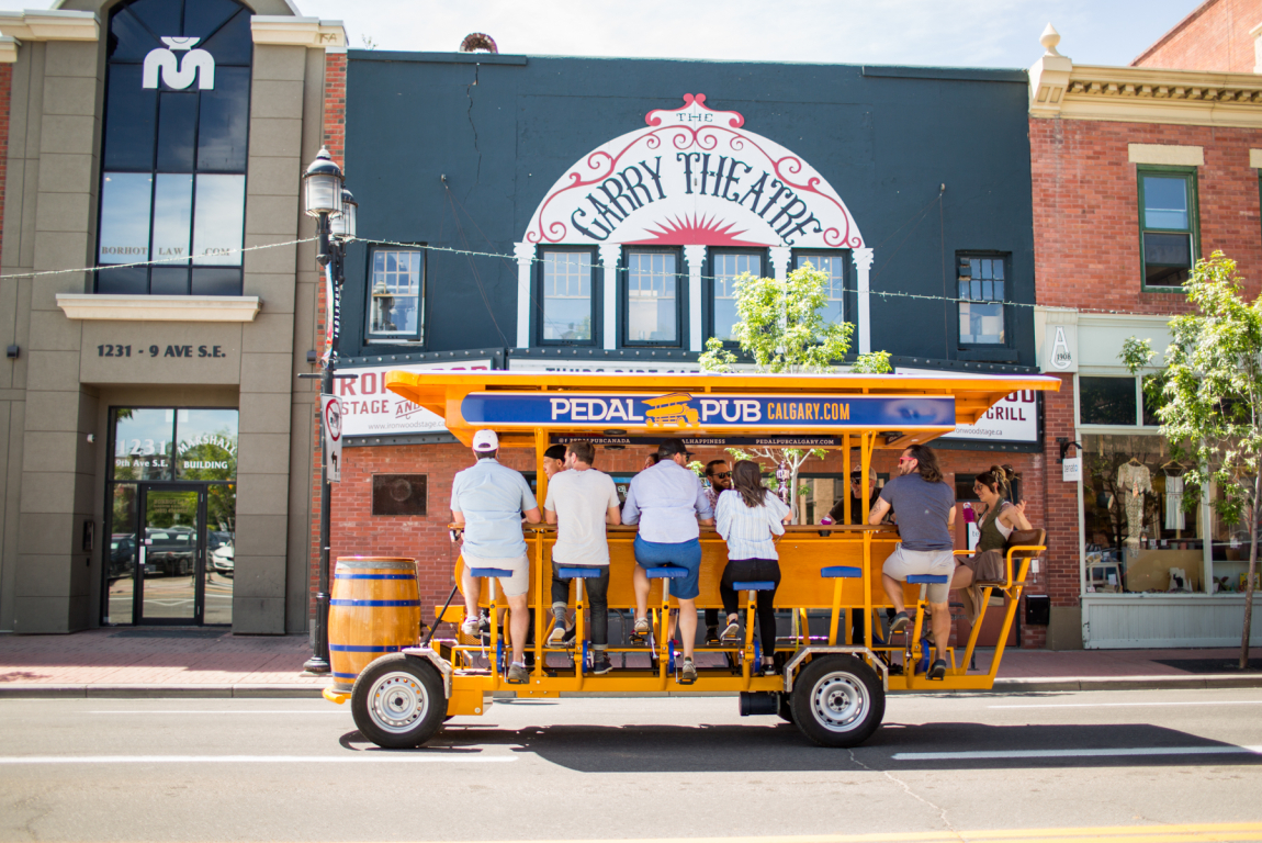 group of people riding on a pedal pub through the streets