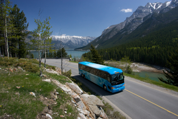 A tour bus driving through Lake Minnewanka in Banff National Park
