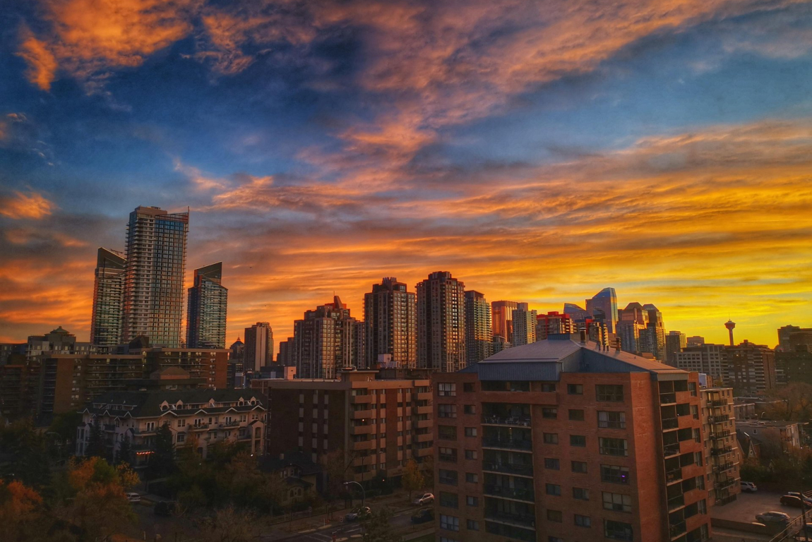 Vibrant sunset sky casting a warm glow over downtown Calgary’s skyline.