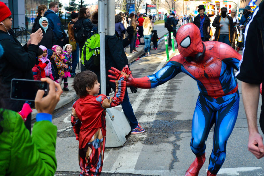 Adult dressed in Spiderman costume high-fives kid at Comic Expo.