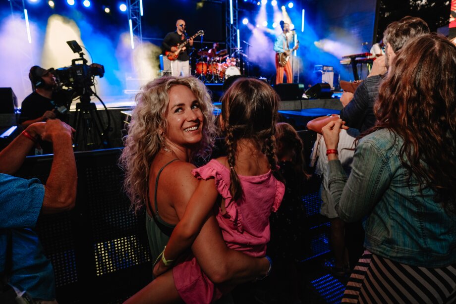 Woman holding her daughter at the Folk festival concert in front of the stage