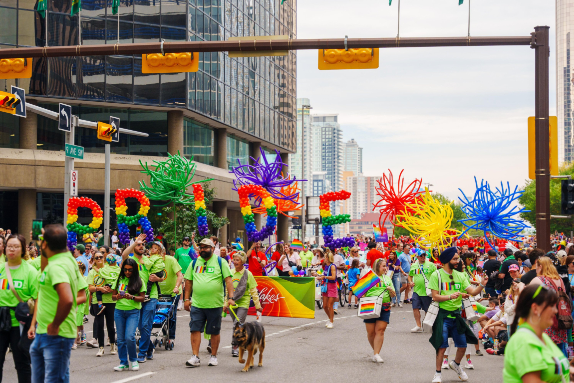 crowd of colourful people walking the pride parade downtown calgary