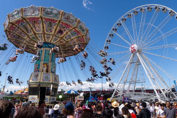 people enjoying the ferris wheel and swings at the Calgary Stampede middway