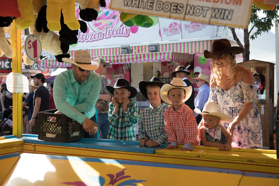 Mother and 4 kids dressed up in cowboy attire playing a midway carnival game