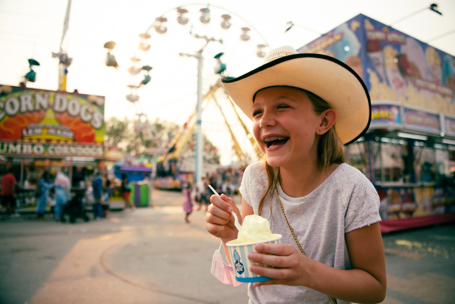 young girl in cowboy hat eating an ice cream at the Calgary Stampede middway