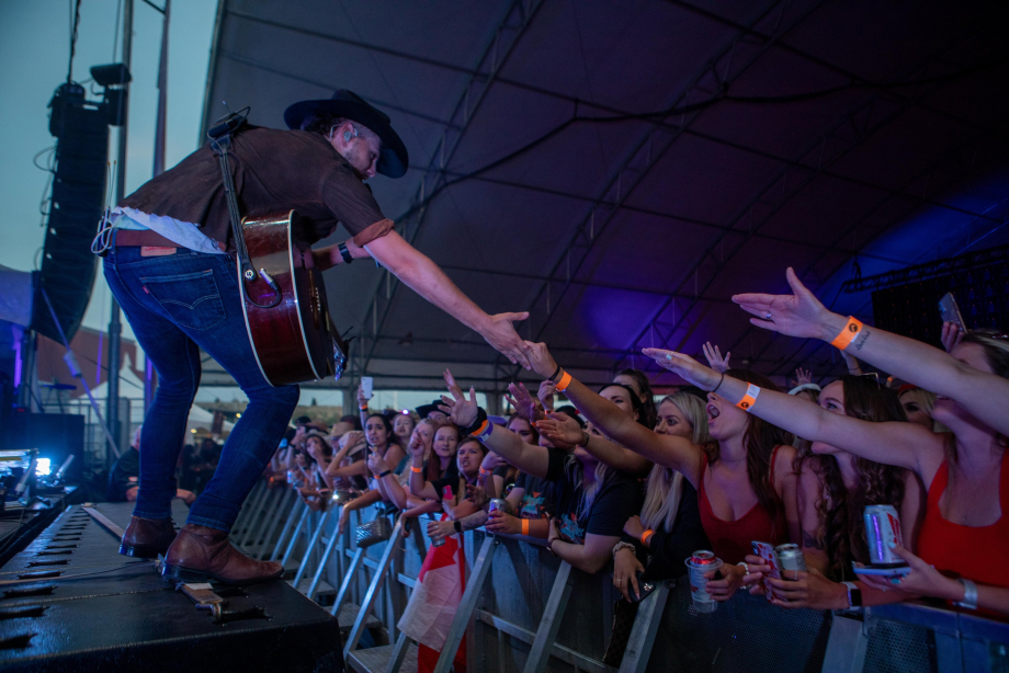 Country performer reaching into crowd at Nashville North concert.