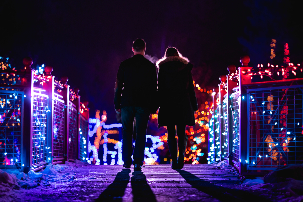 Couple holding hands walking over bridge at ZOOLIGHTS