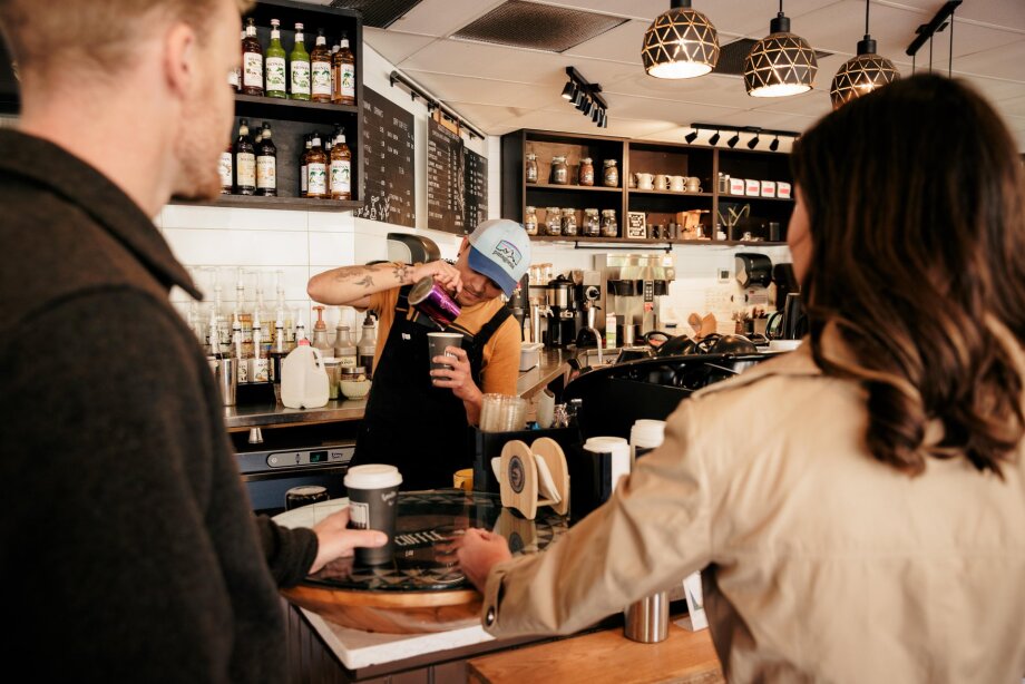 A barista pouring milk into a coffee at Aggudo Coffee Roasters.