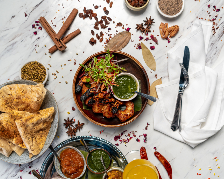 A top down image of a main dish with sides laid out with spice sprinkled throughout the table and cutlery laid out beside it