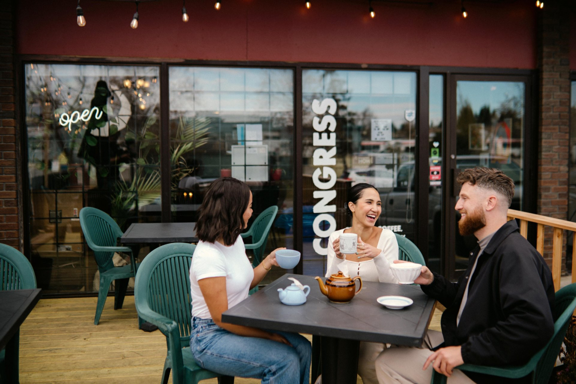 friends sitting at an outdoor patio table enjoying tea from Congress Coffee