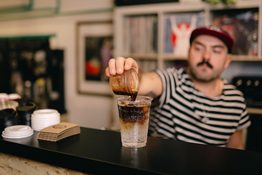 Coffee shop barista puring an espresso into a cup.