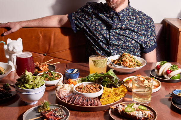 A man sits before a table filled with food and drink at LuLu Bar in Calgary