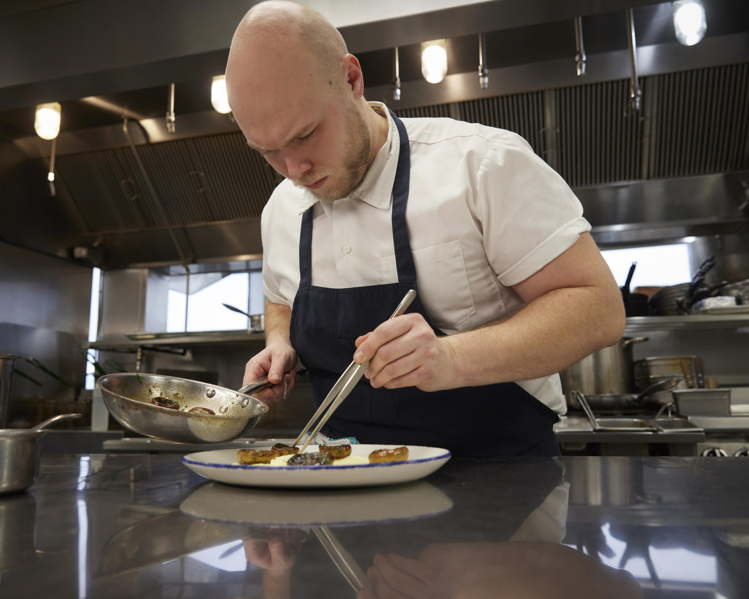 Chef plating a meal with tongs