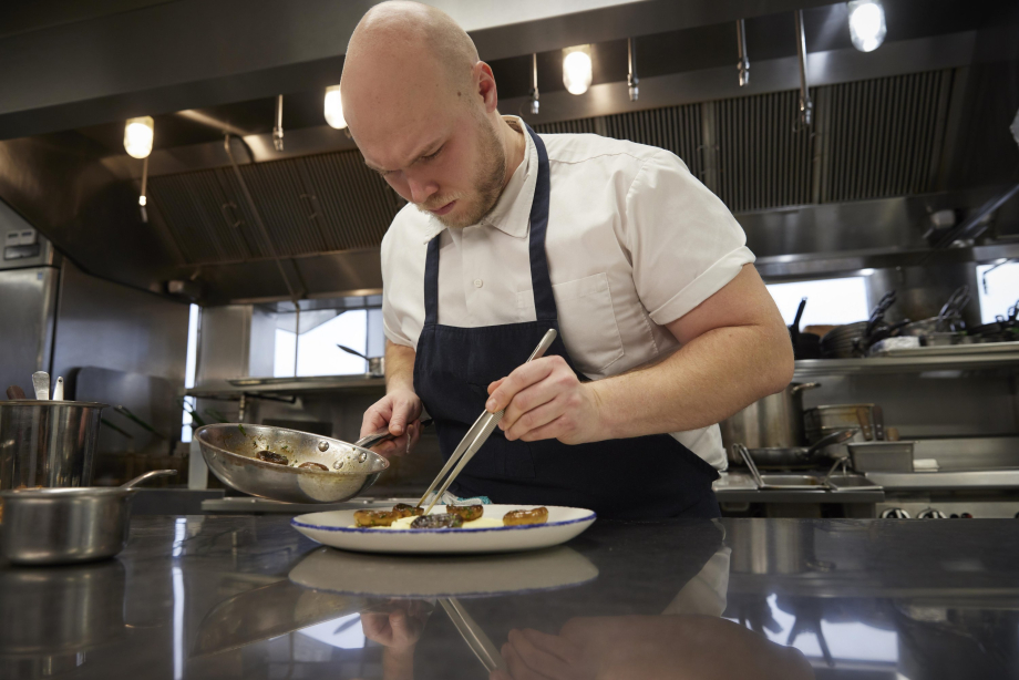 Chef plating a meal with tongs