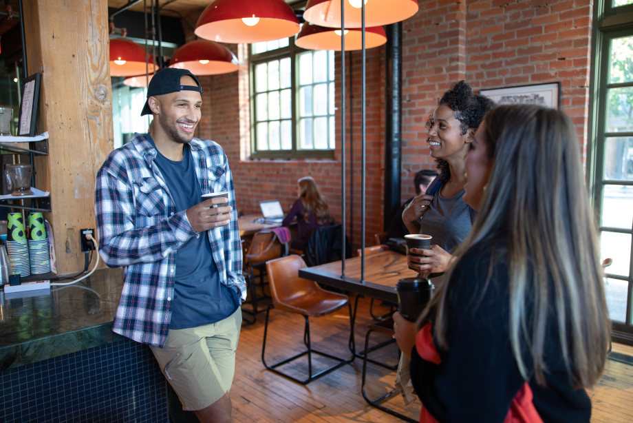 Friends standing around chatting and enjoying coffee at Phil & Sebastian in Calgary