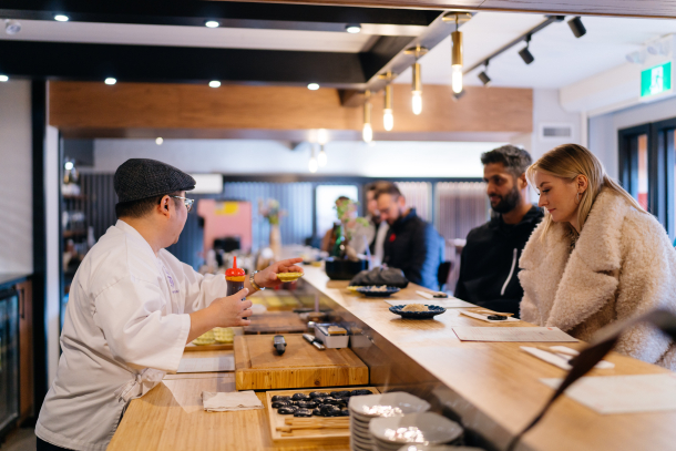 A couple dining at the sushi bar at Satsuki in Kensington as the chef prepares and serves fresh sushi in front of them