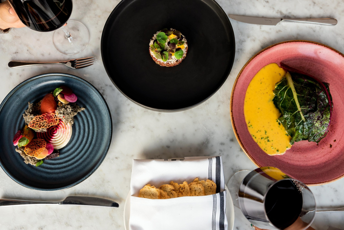 Three dinner plates and a glass of wine