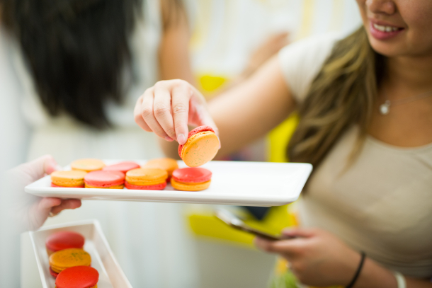 woman picking a red and orange macaron from a dish at Yann Haute Pâtisserie.