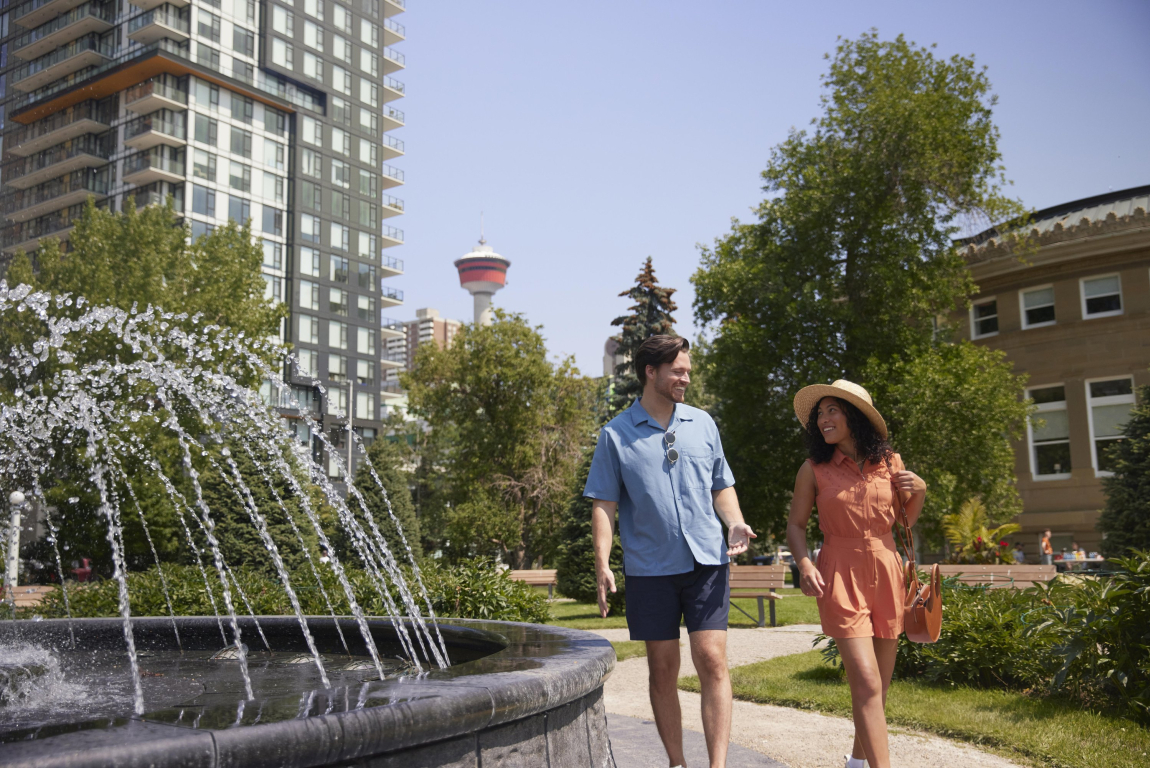 Couple walking around the fountain at Central Memorial Park downtown Calgary
