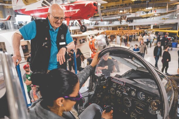 A staff member helps a visitor check out the cockpit of a plane at the Hanger Flight Museum