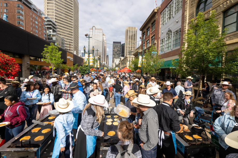 Crowd of people in western wear gathered downtown for a pancake breakfast