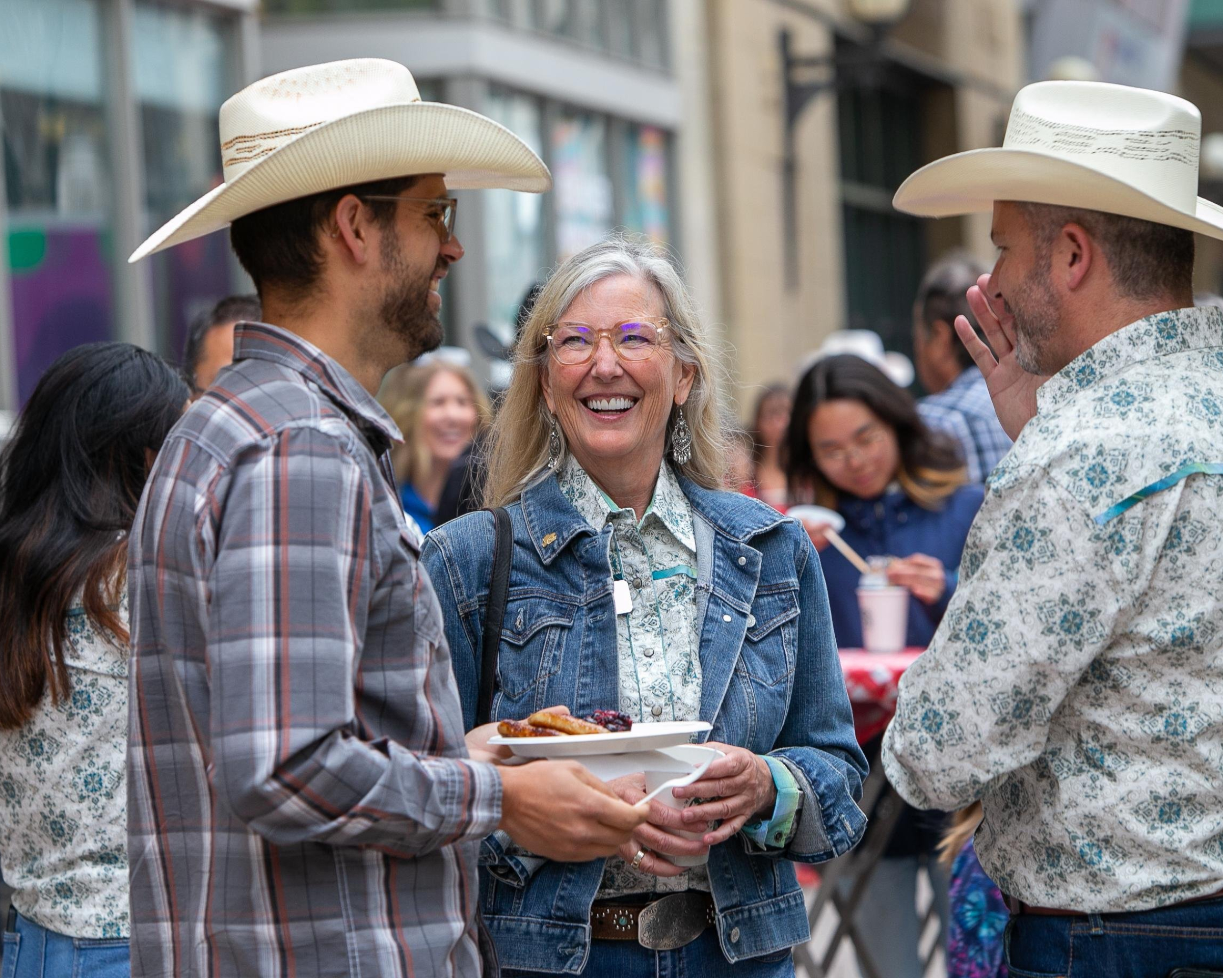 3 people dressed in western wear chatting and eating a pancake breakfast