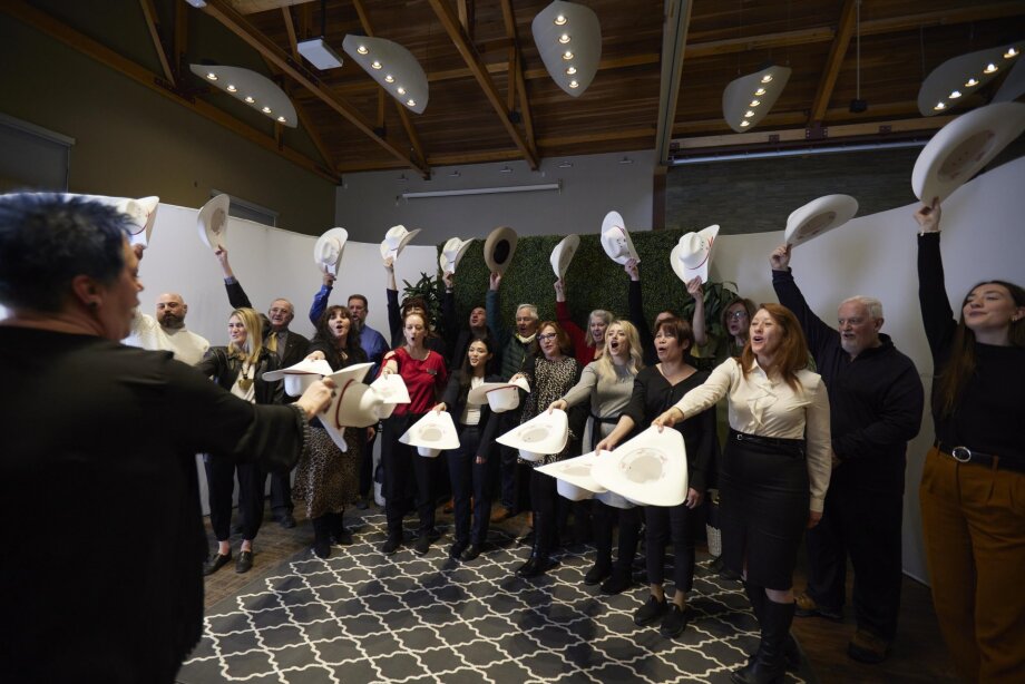 Group of people tipping their hats in a white hat ceremony