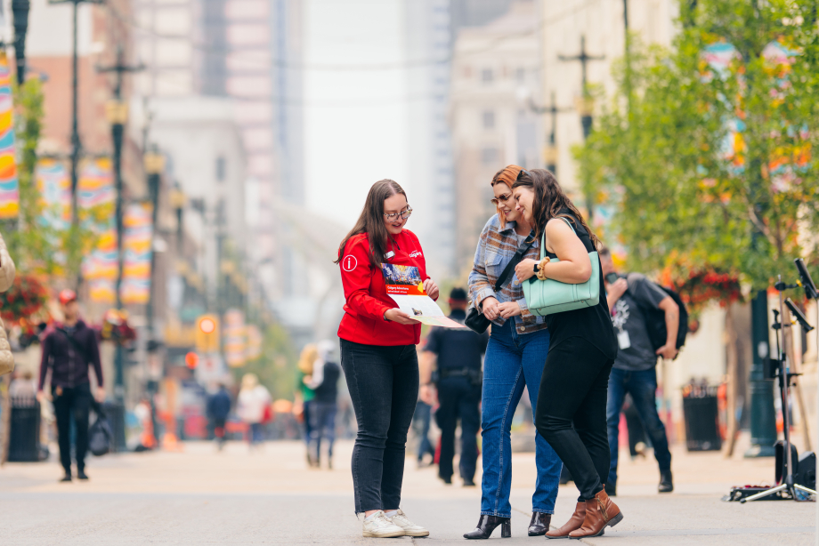A local guide showing a map to a couple of tourists on Stephen Avenue in downtown Calgary