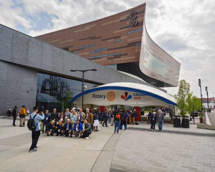 Group of Rotary attendees posing for a photo in front of a large entrance gate