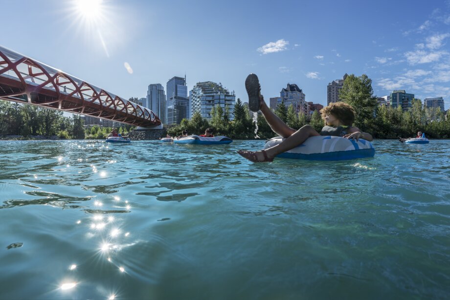 A group of people floating down the Bow River near the Peace Bridge.