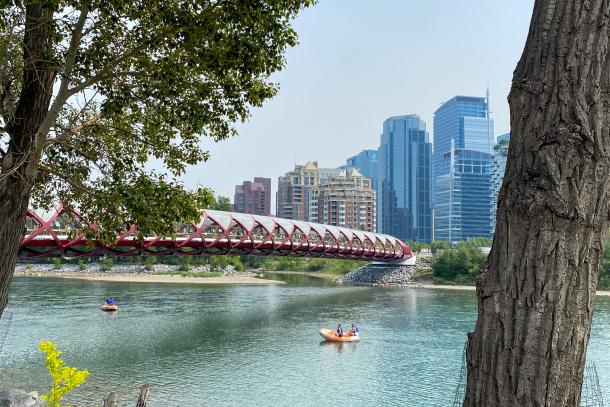 People floating in rafts down the bow river and under the peace bridge