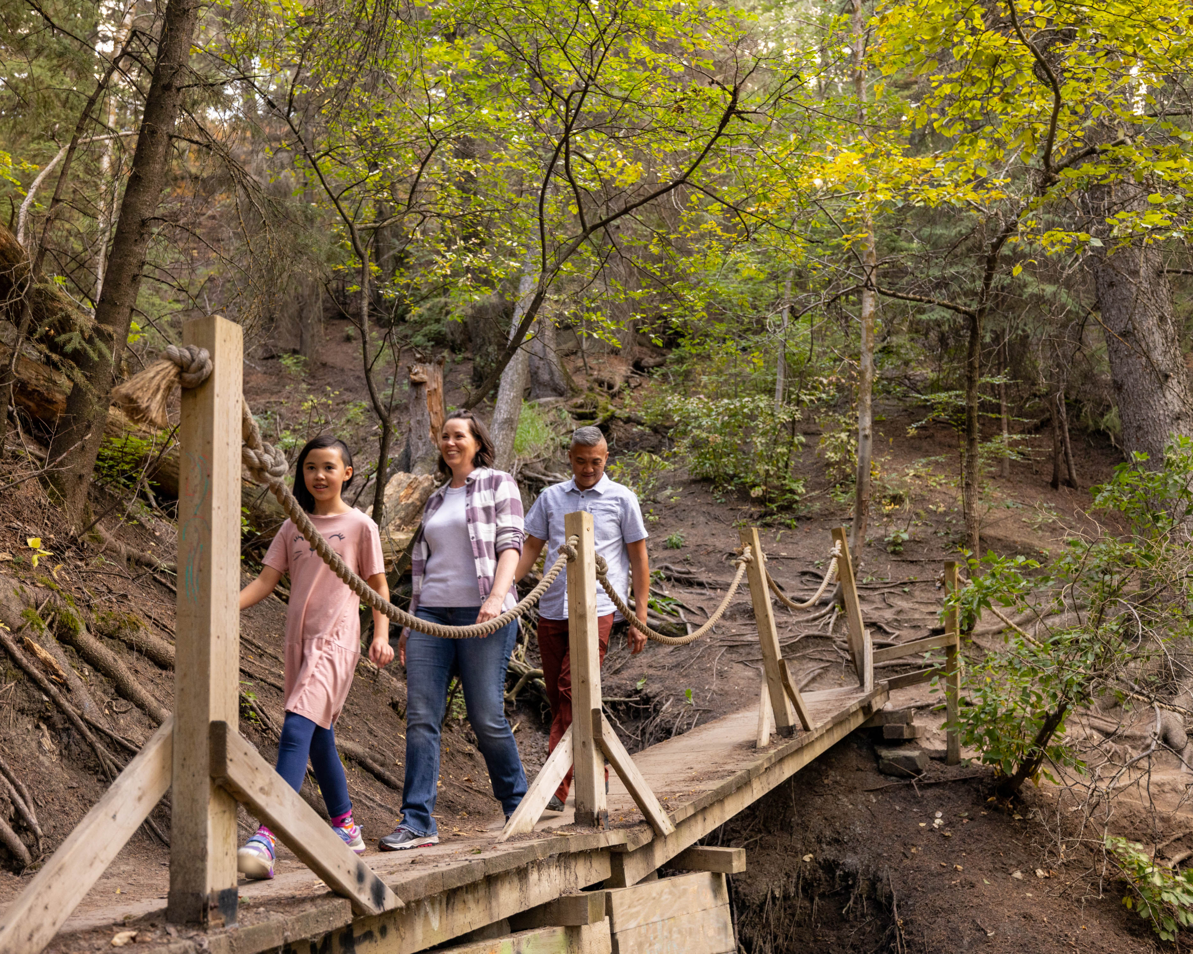 family hiking along a wooden bridge in the woods of the Douglas Fir trail