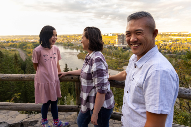Family of 3 overlooking the bow river from a viewpoint on a hiking trail