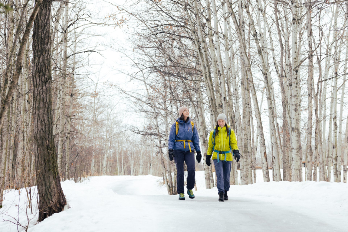two friends hiking through Fish Creek Provincial Park in winter