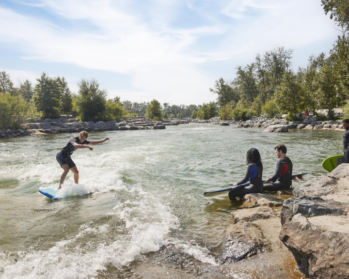 Group of friends surfing in a river