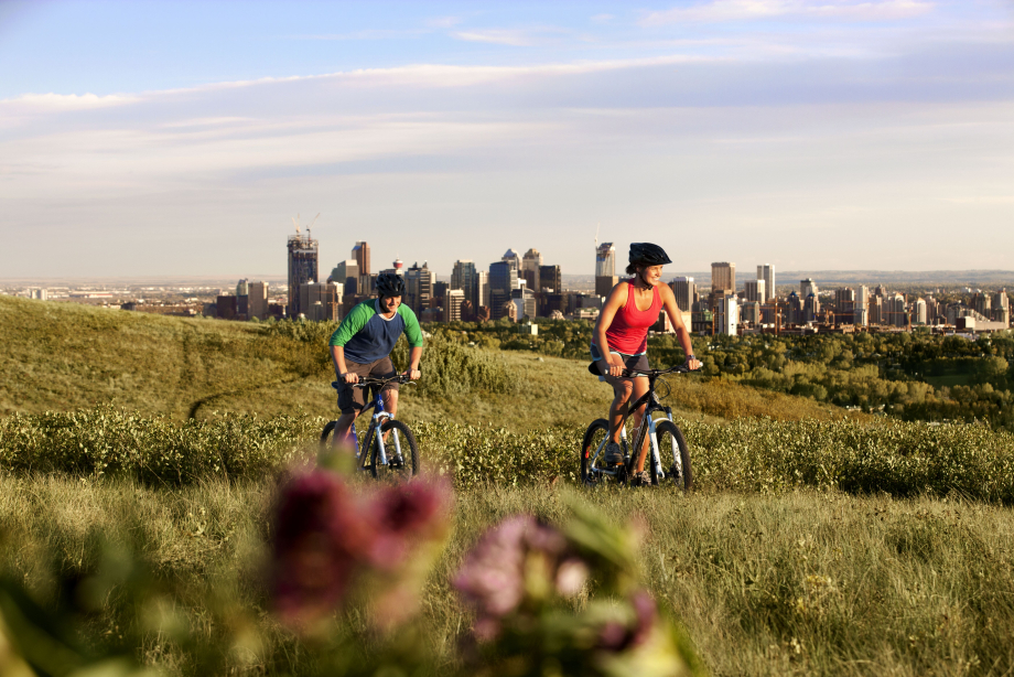Couple mountain biking at Nose Hill Park with views of downtown Calgary
